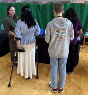 Young people at the booth, seen from behind, with our team.