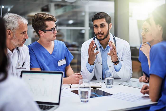 Doctor discussing integrated MedTech solutions with medical staff to enhance healthcare outcomes, optimize efficiency, and accelerate patient impact.