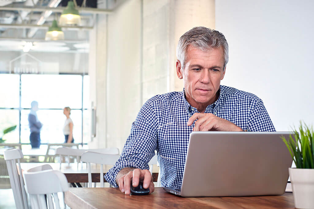 man looking at laptop in cafe