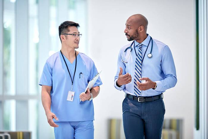 two HCPs walking and talking in hallway