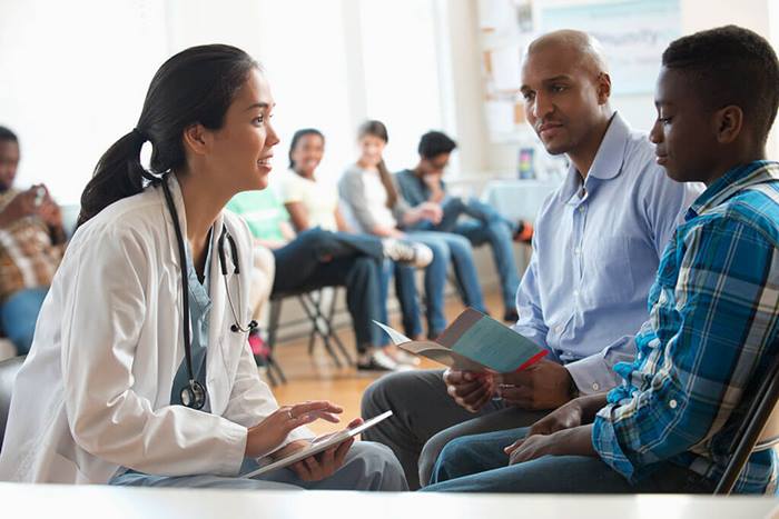 Doctor using digital tablet with patients in volunteer clinic