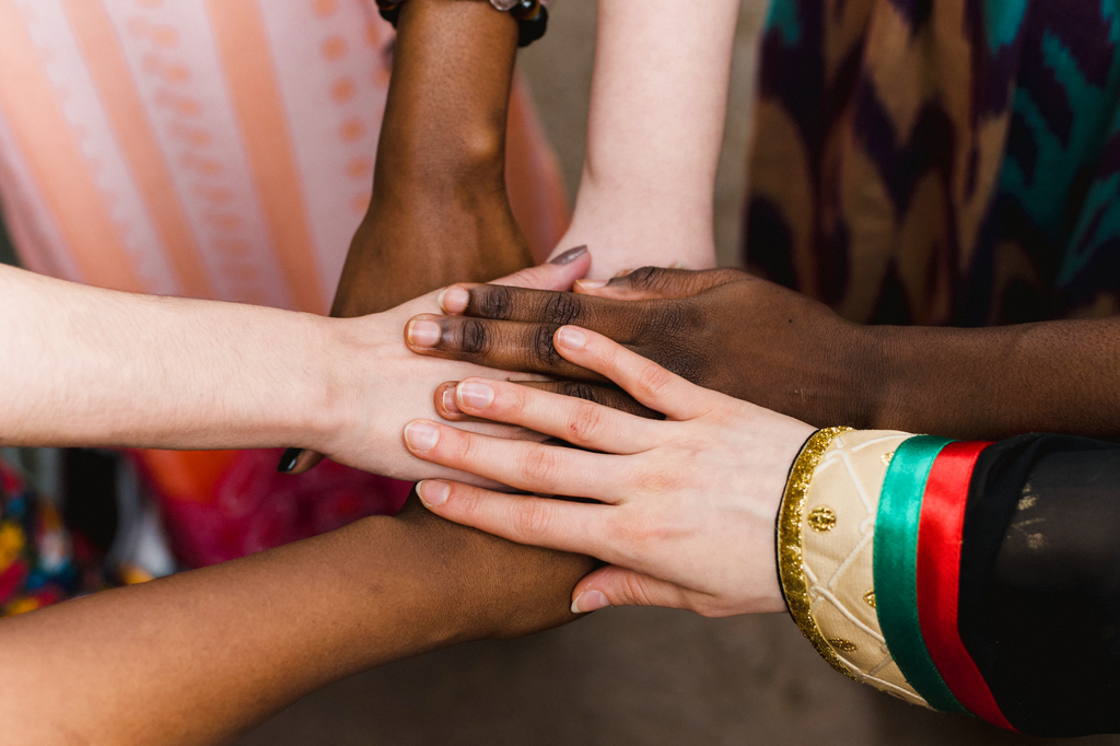 Diverse people stand in a circle together and hold hands