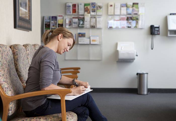 Woman filling out forms doctors waiting room