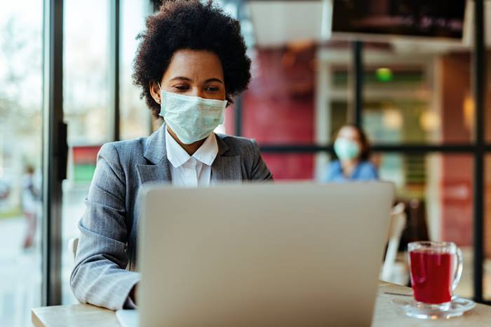 Businesswoman with mask working in coffee shop