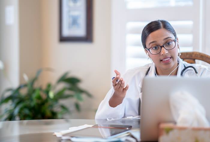 Female doctor working from home and talking to her patients via video call