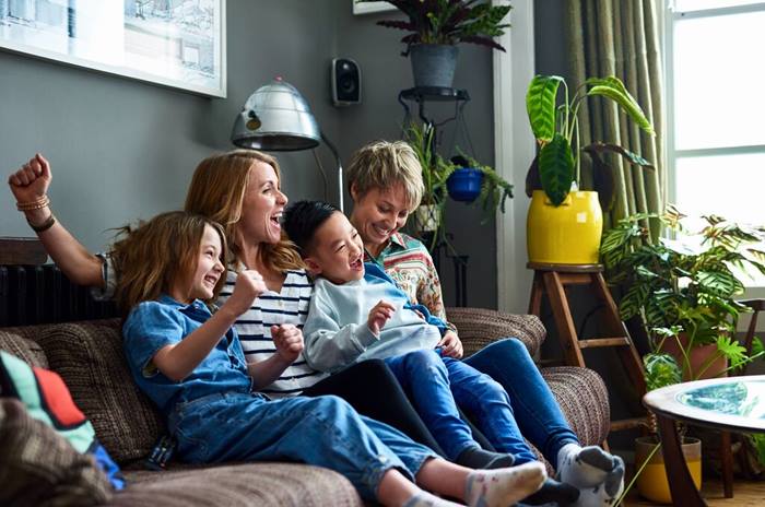 Cheerful family with two mums watching tv at home