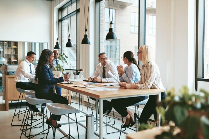 group of smiling businesspeople discussing paperwork together during a meeting