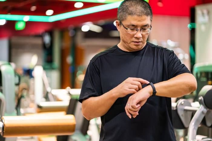 Asian man using a fitness band to track his workout