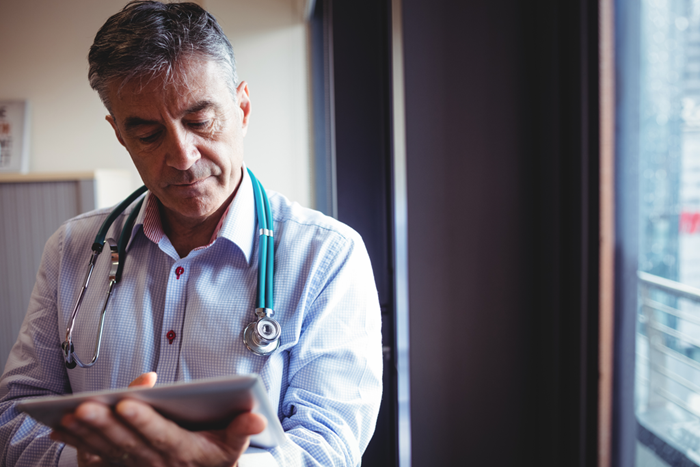 Male doctor using tablet standing in hospital