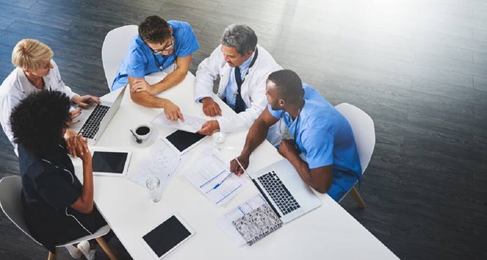 Team of healthcare workers meeting with laptops around table