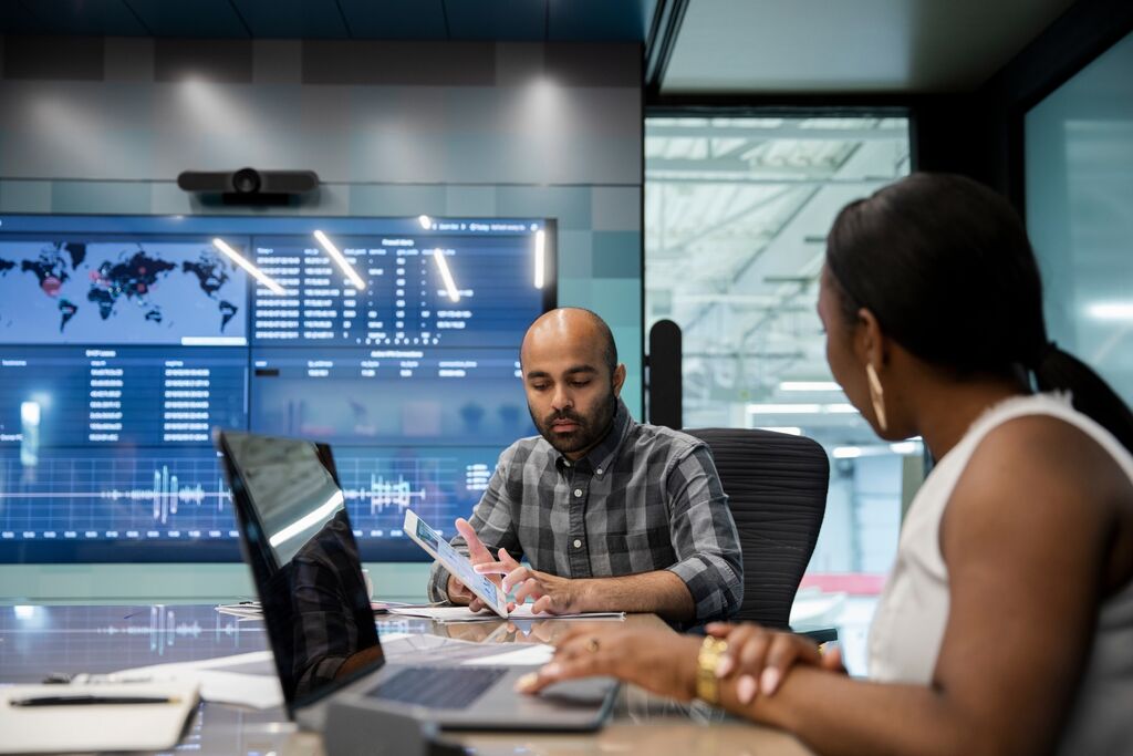 -Colleagues planning work on digital devices in modern meeting room