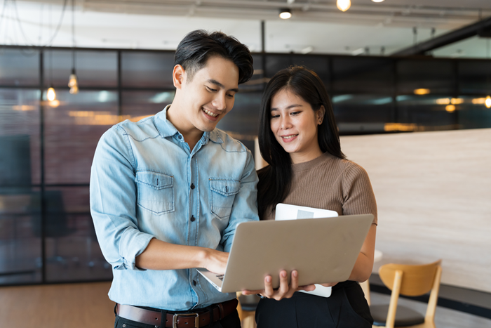Man and woman standing brainstorming together and working with laptop c