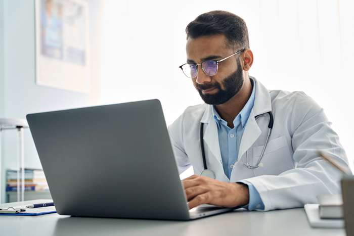 Indian doctor using laptop computer at work in hospital