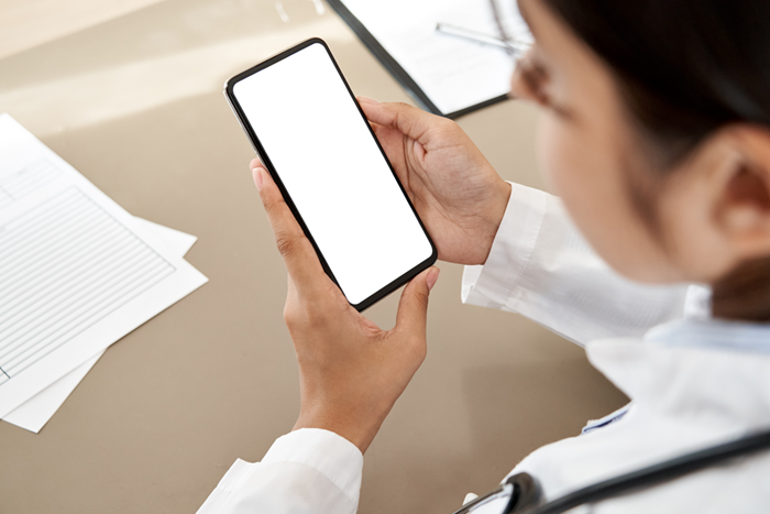 Indian doctor holding cell phone with app mock up white screen