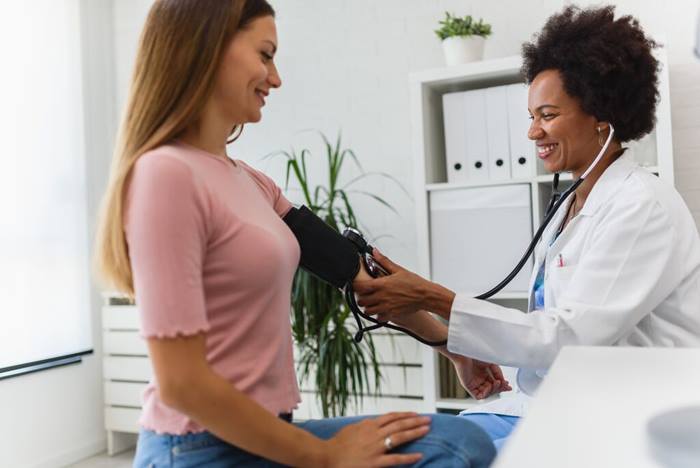 Doctor measuring blood pressure of a young woman