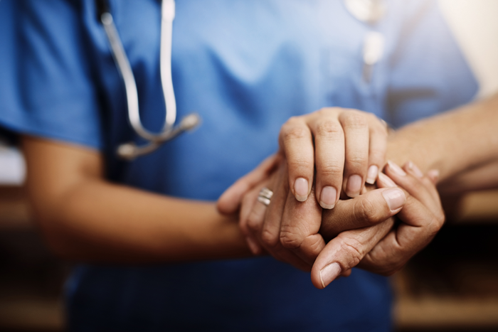 Closeup of doctor holding hands with patient