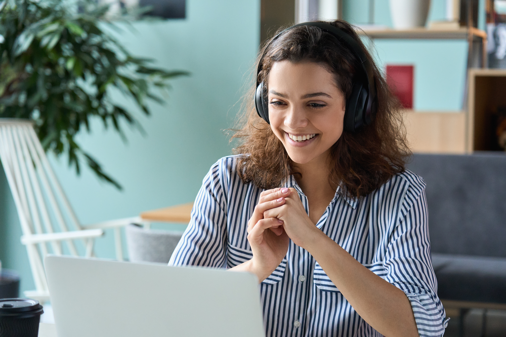Happy employee wearing headphones having video conference on laptop