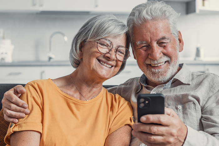 Happy mature couple using smartphone together at home