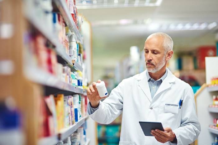 Mature male pharmacist using a tablet working in a pharmacy