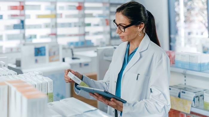 Pharmacist using tablet checking medicine