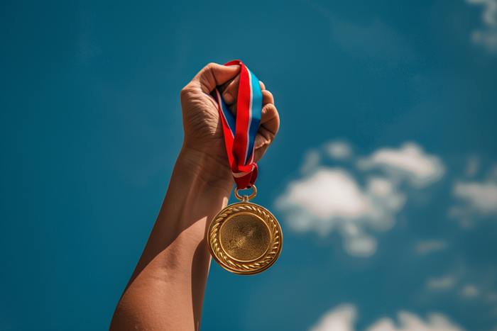 Hand holding a golden medal