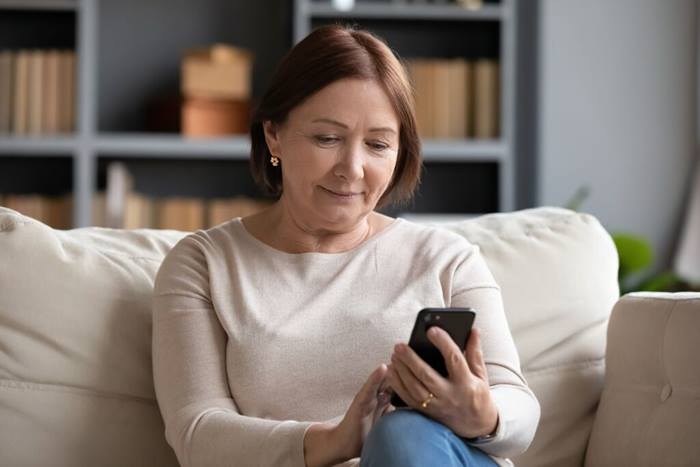 Focused mature woman using phone at home