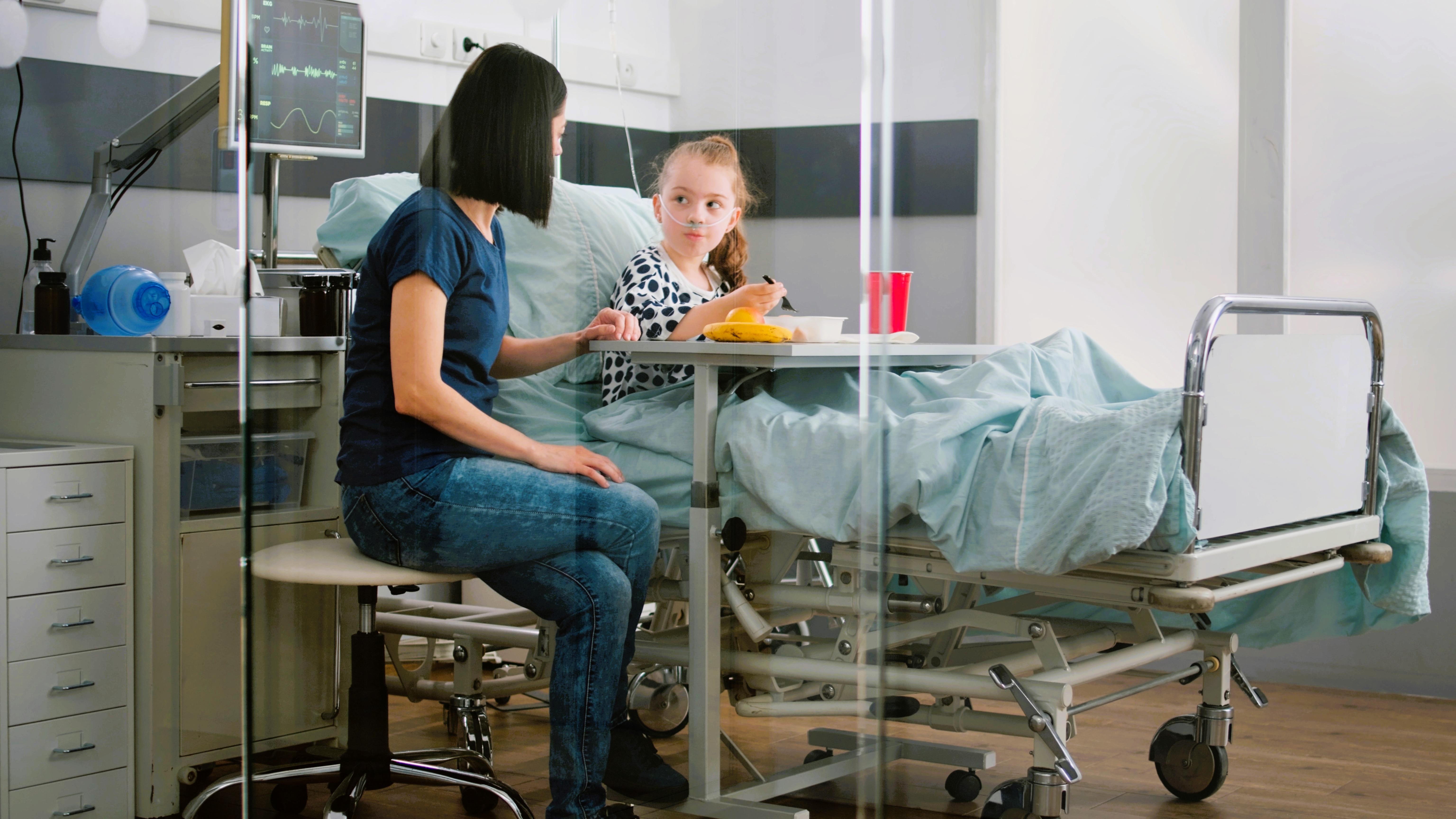 Sick child sitting in bed eating healthy food during lunch in hospital