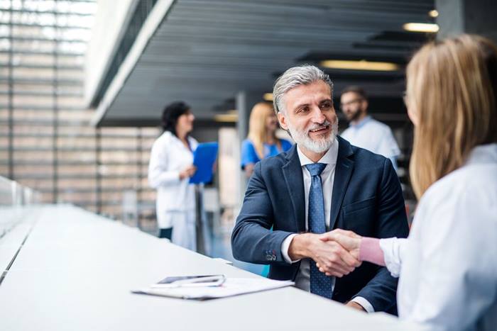 Doctors talking to pharmaceutical sales representative shaking hands